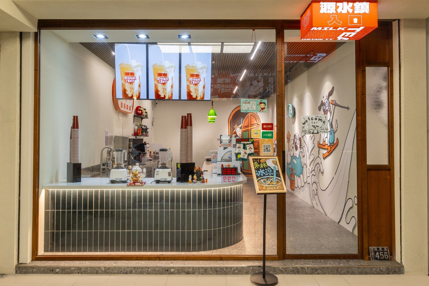 源水逢甲店夜間店面，整面玻璃內是弧形吧台與綠色長條磚檯面，右側牆是品牌手繪插畫，上方掛橘色發光招牌